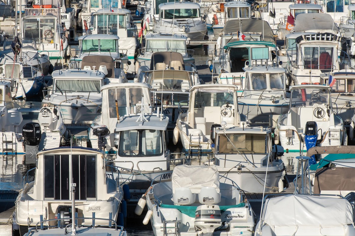 Bateaux à moteur amarrés côte à côte dans une marina, avec cabines, amarres et pare-battages, illustration générique.